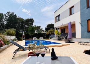 une maison avec une piscine et une table avec des verres à vin dans l'établissement Casa Tres Cales, à L'Ametlla de Mar