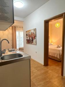 a kitchen with a sink and a room with a bed at Apartmens Xhenis Lux in Ulcinj