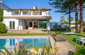 a villa with a swimming pool in front of a house at Exotic Beachfront Retreat Handcrafted Bohemian Luxury in Cádiz