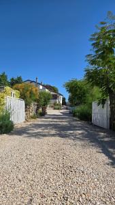 a gravel road with a white fence and trees at Apartman Luce in Krk +16 photos