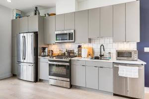 ワシントンにあるWalkable Columbia Heights Condo with Rooftop Deck!の白いキャビネットとステンレス製の電化製品を備えたキッチン