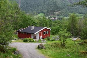 a red house on a hill next to a road at Skogshytte in Bjordal