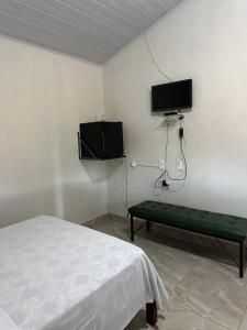 a bedroom with a bed and a tv on the wall at Chalés Relíquias da Canastra Il in São Roque de Minas