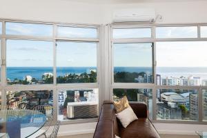 sala de estar con sofá y ventanas grandes en Luxury Surround Sea View Apartment, en Salvador