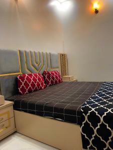 a bed in a room with two red pillows on it at Palace inn Guest House in Karachi