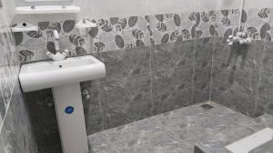 a bathroom with a sink and a tiled wall at Palace inn Guest House in Karachi
