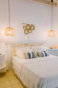 a bedroom with a white bed with two pendant lights at Lampi's House in Patmos