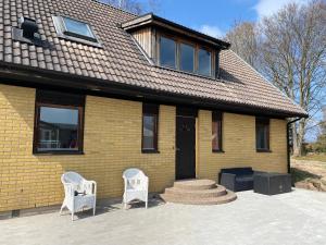 a yellow brick house with two white chairs in front of it at PALEO House in Kristianstad