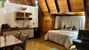 a bedroom with a bed and a kitchen with a table at Pousada Lua chalé in Blumenau