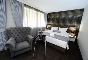 ein Schlafzimmer mit einem Bett und einem Stuhl in der Unterkunft Alexandar Square Boutique Hotel in Skopje