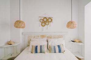 a bedroom with a white bed with two pendant lights at Lampi's House in Patmos