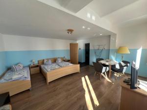 a room with two beds and a table and a tv at Ferienwohnungen Hennig in Ahlbeck