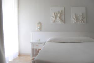a white bedroom with a white bed and two pictures on the wall at Hotel Acquamarina in Donnalucata