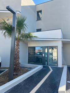 een wit gebouw met een palmboom ervoor bij Bord de mer exceptionnel in Marseillan