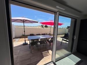 a patio with tables and umbrellas on a deck at Bord de mer exceptionnel label 4 étoiles "Clevacances" in Marseillan