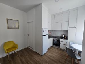 a kitchen with white cabinets and a table and a yellow chair at Casa da Praça in Condeixa a Nova