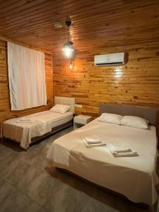two beds in a room with wooden walls at Atlas Bungalows in Kumluca