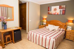a hotel room with a bed and a desk and a mirror at Hotel Noguera El Albir in Albir