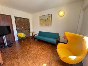 a living room with a blue couch and a yellow chair at Sesimbra Universal in Sesimbra +4 photos