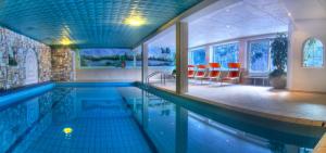 einen Pool in einem Haus mit roten Stühlen in der Unterkunft Sporthotel Spoegler in Klobenstein