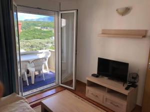 a living room with a tv and a balcony with a table at Apartments Nera in Utjeha