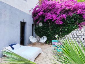 a room with a bed and two chairs and purple flowers at BOUTIQUE HOSTEL BY Cassis in Cassis