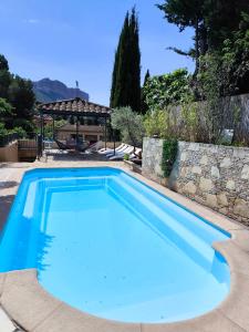 a large blue swimming pool with a stone wall at BOUTIQUE HOSTEL BY Cassis in Cassis