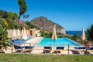een zwembad met parasols en stoelen en de oceaan bij CefalHome - TORRE in Cefalù