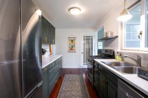 a kitchen with green cabinets and a stainless steel refrigerator at Berkshire Vacation Rentals: Great Barrington Walkable To Lake And Town in Great Barrington