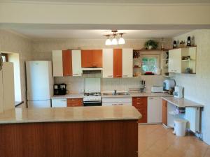 a large kitchen with white appliances and wooden cabinets at Casa de vacanță Tarnița in Someşu Cald