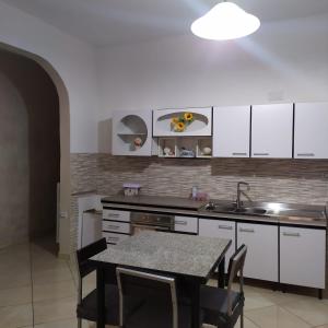 ポルト・チェザーレオにあるCasa Antonellaの白いキャビネットとテーブルと椅子のあるキッチン