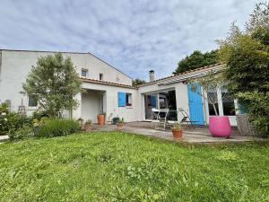 ein weißes Haus mit einem Garten mit einem rosa Stuhl in der Unterkunft Maison 4 pièces avec parking et terrasse à Saint Georges d'Oléron - FR-1-246A-355 in Saint-Georges-dʼOléron