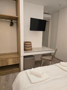 a room with a bed and a desk with a television at Hotel Alexandra in Skala