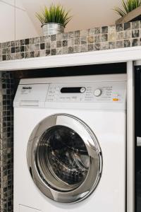 ベルゲンにあるDINBNB Apartments l 200m to Bryggen l Luxury 2 BR l 2min to Floibanenの植物のあるキッチンに洗濯機と乾燥機がある