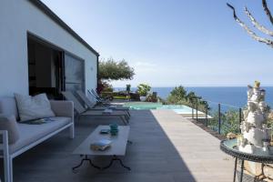 un patio con sofá, mesa y el océano en Villa Talia 4 by Massimo Villas, en Cefalú