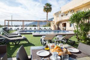 a table with food and drinks on a patio with a pool at Hotel Noguera El Albir in Albir