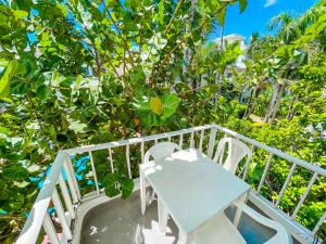 蓬塔卡纳CARIBBEAN Paradise TROPICAL HOTEL with VIEW Los Corales WiFi Beach CLUB & SPA的树木繁茂的阳台配有白色的桌椅