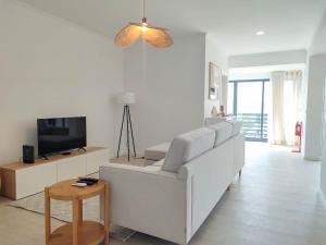 Una sala de estar con un sofá blanco y un televisor. en Serena, en Madalena