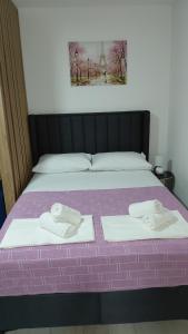 Una cama morada con dos toallas encima. en Apartman Vuk 15, en Budva