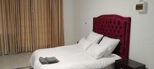 a bedroom with a large bed with a red headboard at Villa paradiso in Centurion