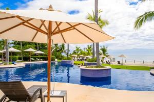 a pool at the resort with chairs and an umbrella at Alamar Vallarta vta in Cruz de Huanacaxtle
