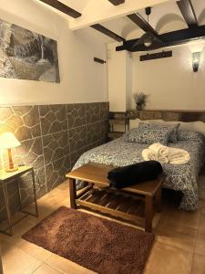 a bedroom with a bed with a table and a bench at El Refugio de Casa Nieves in Villahermosa del Río