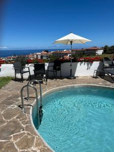 basen z parasolem, krzesłami i stołem w obiekcie Casa Janni with heated private pool w Puerto de la Cruz