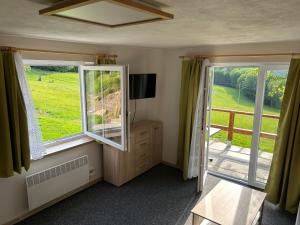 a living room with two windows and a television at Chata Jezevec - samostatný apartmán in Nýrsko