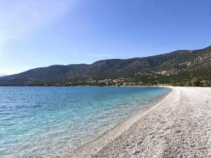 a beach with blue water and mountains in the background at Grey house in Didyma
