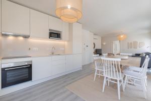 una cucina con mobili bianchi, tavolo e sedie di Peniche Hideout a Peniche