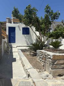a white house with a blue door and a tree at Aosa seaside home in Áyios Stéfanos +6 photos