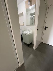 a white bathroom with a sink and a mirror at Bright and peaceful studio with extendable bed in Palaiseau +12 photos