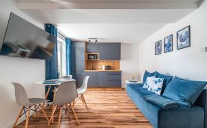 salon z niebieską kanapą, stołem i krzesłami w obiekcie Apartamenty Dostoja we Władysławowie