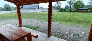 a wooden bench sitting on a porch with a field at Cazare Valea Dinozaurilor in Sibişel